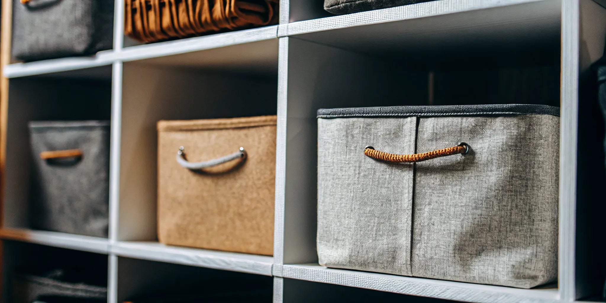 Fabric storage bins for shelves with handles, neatly organized in a cubby unit.