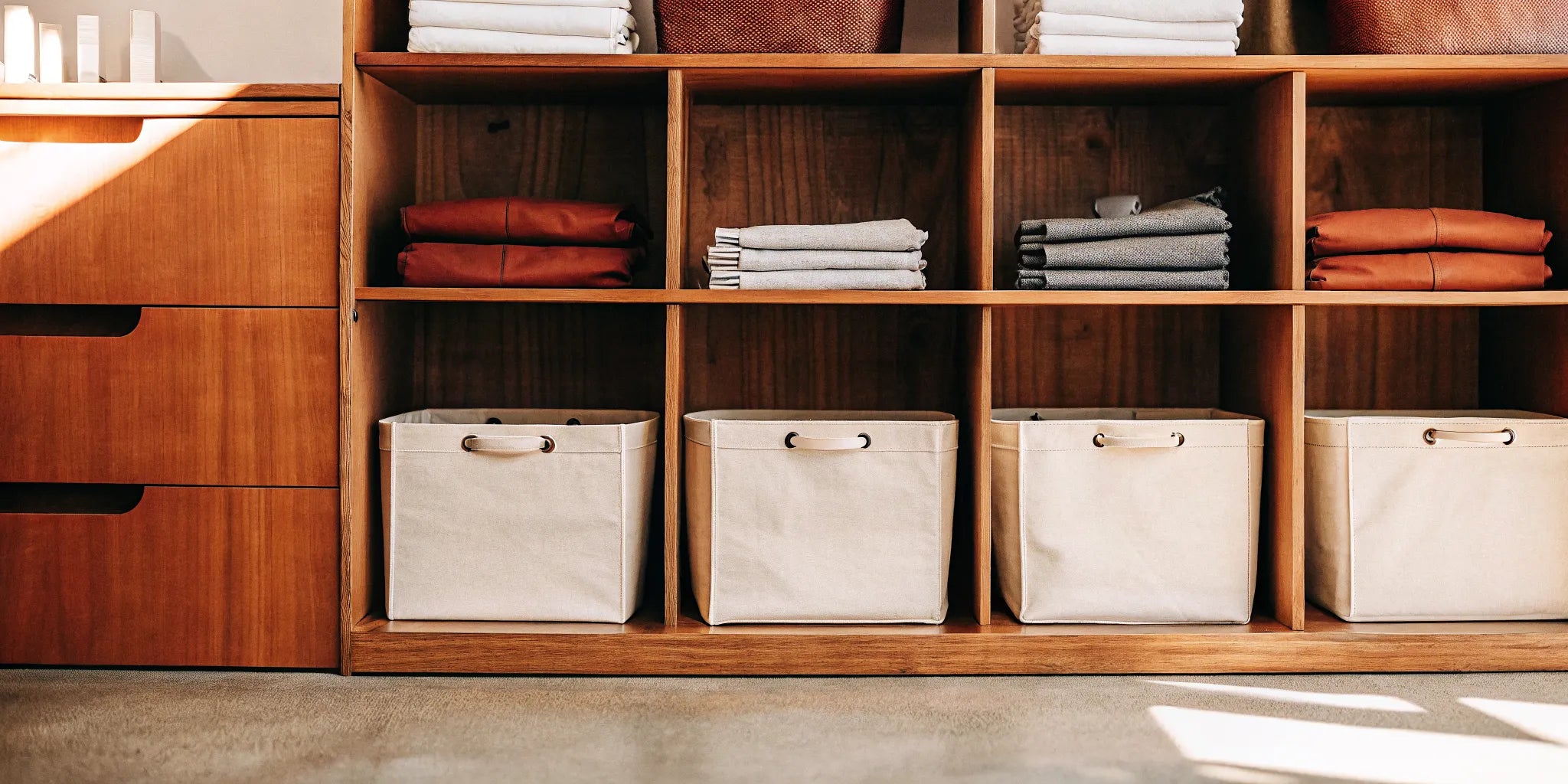 Clothes storage bins for shelves holding folded clothes in a tidy wooden cubby.