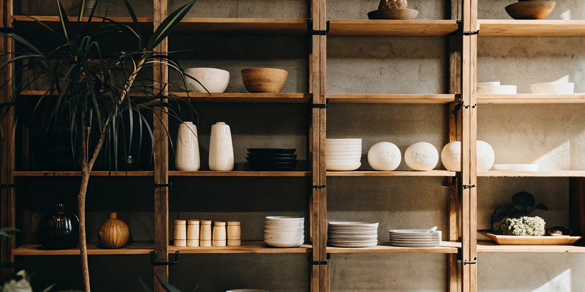 A wooden wall hanging shelf displaying minimalist decor and simple ceramic dishes.