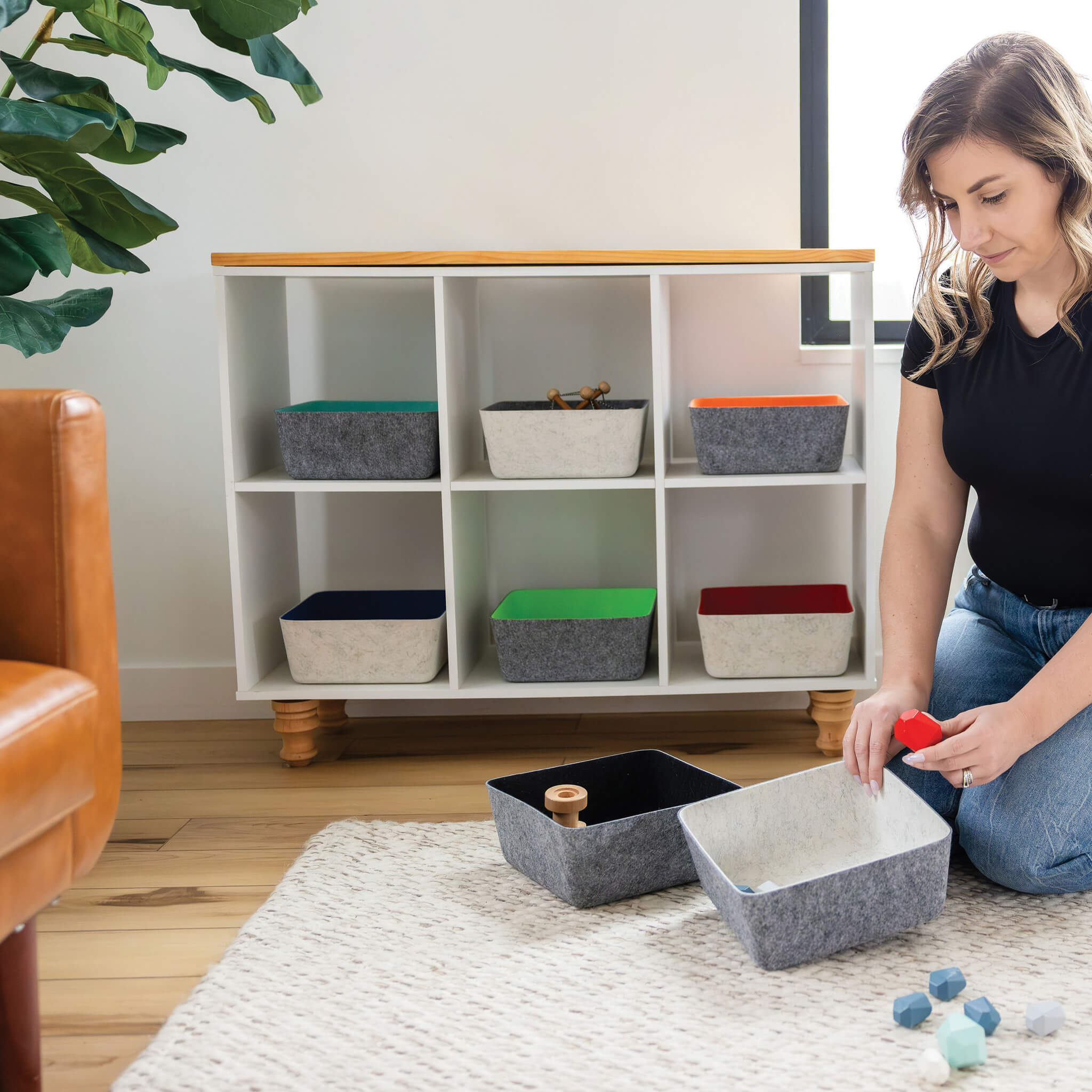 Woman organizing recycled felt organizing sorting storage bins in a living room setting