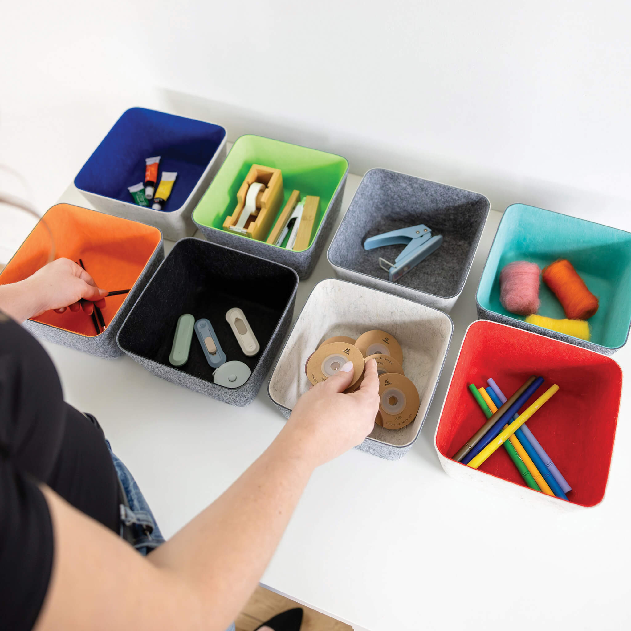 Colorful recycled felt organizing sorting storage bins with various items on a white surface