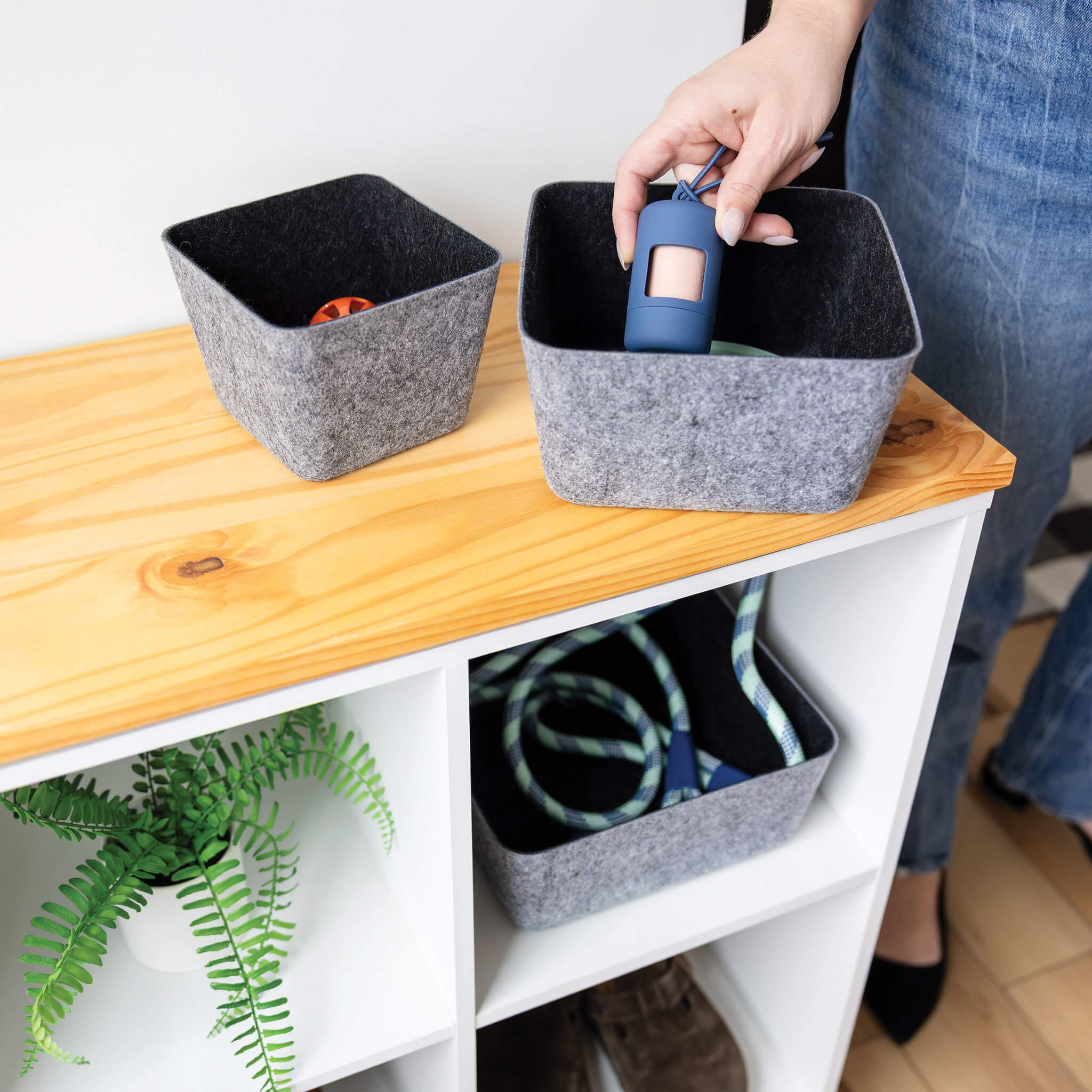 Person organizing items into charcoal recycled felt organizing sorting storage bins on a wooden surface.